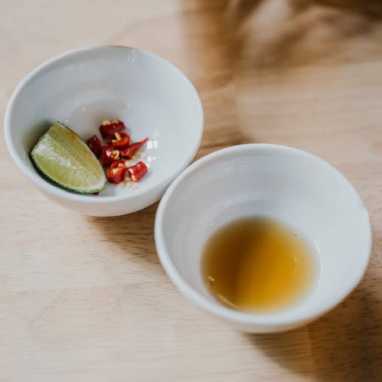 sliced lime and chili peppers in white ceramic bowl