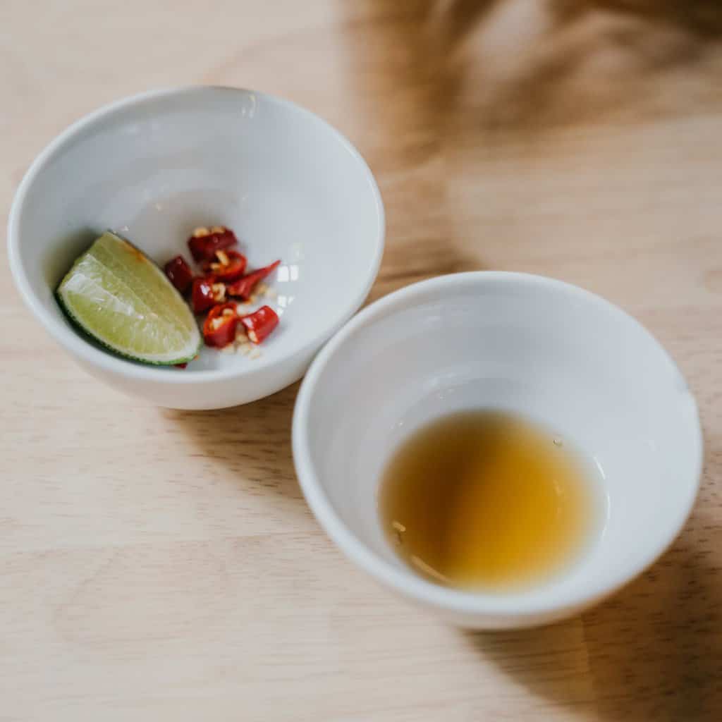 sliced lime and chili peppers in white ceramic bowl